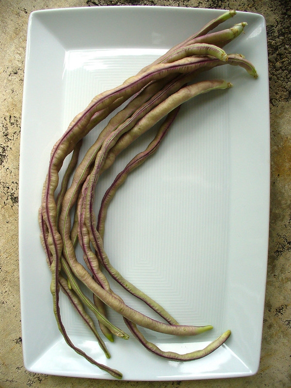 Plate of harvested long bean pods with reddish mottling.