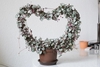 Potted vining plant trained on a heart-shaped trellis.