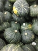 Large, green kabocha squash piled at a market