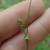 Spike of small green flowers resting against two fingers.